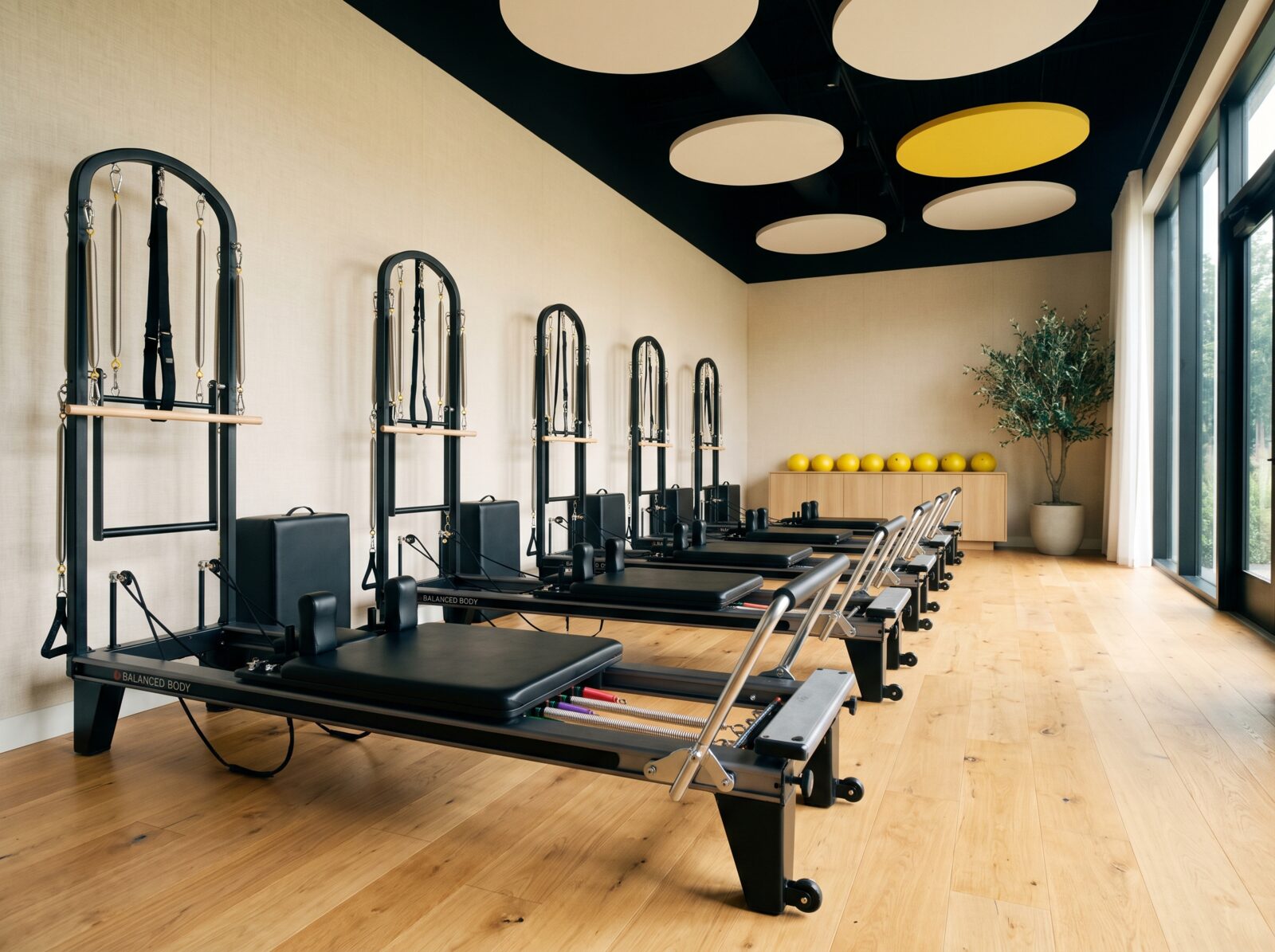 A row of reformers along the wall of the Aria Pilates studio